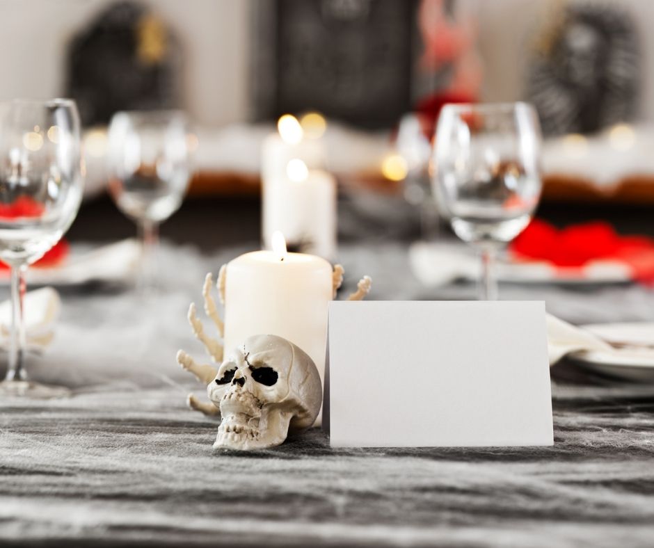 table set with candles, wine glass, and skulls for a halloween themed dinner costume together