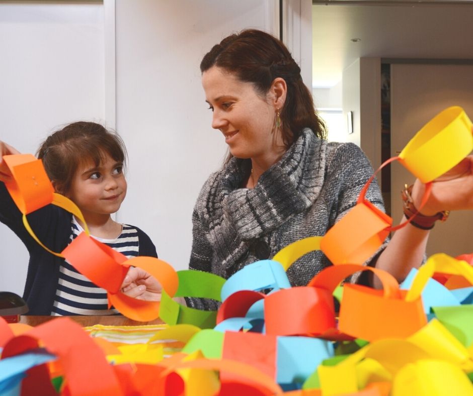 mother with daughter creating a colorful paper chain link, their debt payoff visual aid