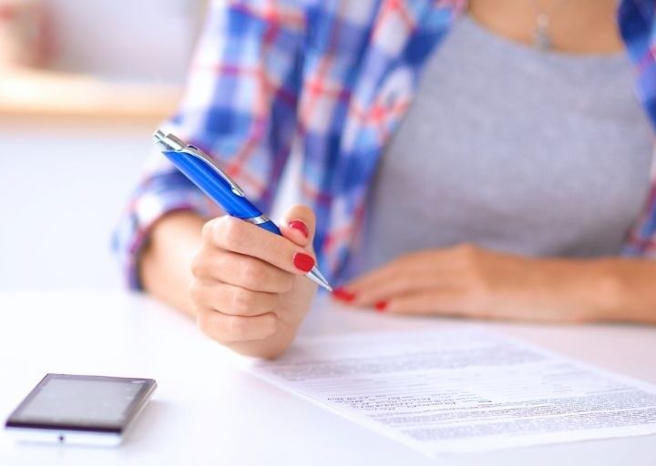 woman in blue plaid shirt with calculator working on money management worksheets pdf