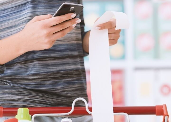 woman in grocery store scanning receipt into fetch and ibotta apps