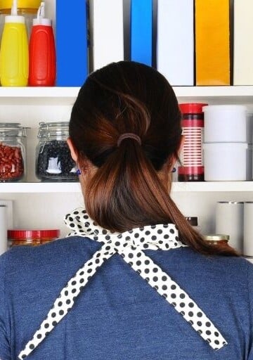 woman facing pantry wide open, trying to figure out what to cook