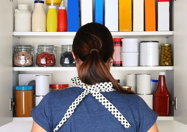 woman facing pantry wide open, trying to figure out what to cook