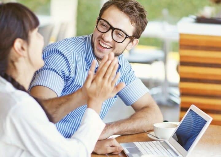 couple smiling and giving a high five while working on couple's financial goals worksheet