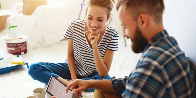 couple having fun looking at tablet that has money saving challenges for couples on it