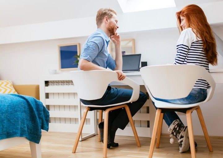 married couple sitting in white chairs having a financial meeting with spouse