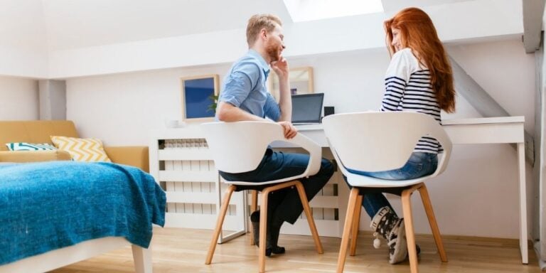 married couple sitting in white chairs having a financial meeting with spouse