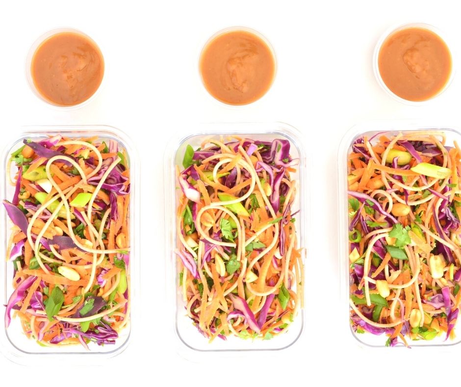 three bento boxes of cold thai noodle salad with containers of peanut sauce