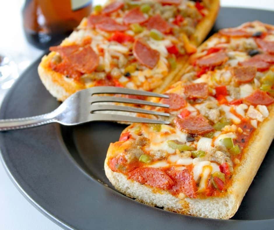 two french bread pizzas on a black plate, an easy meal for a group of 20