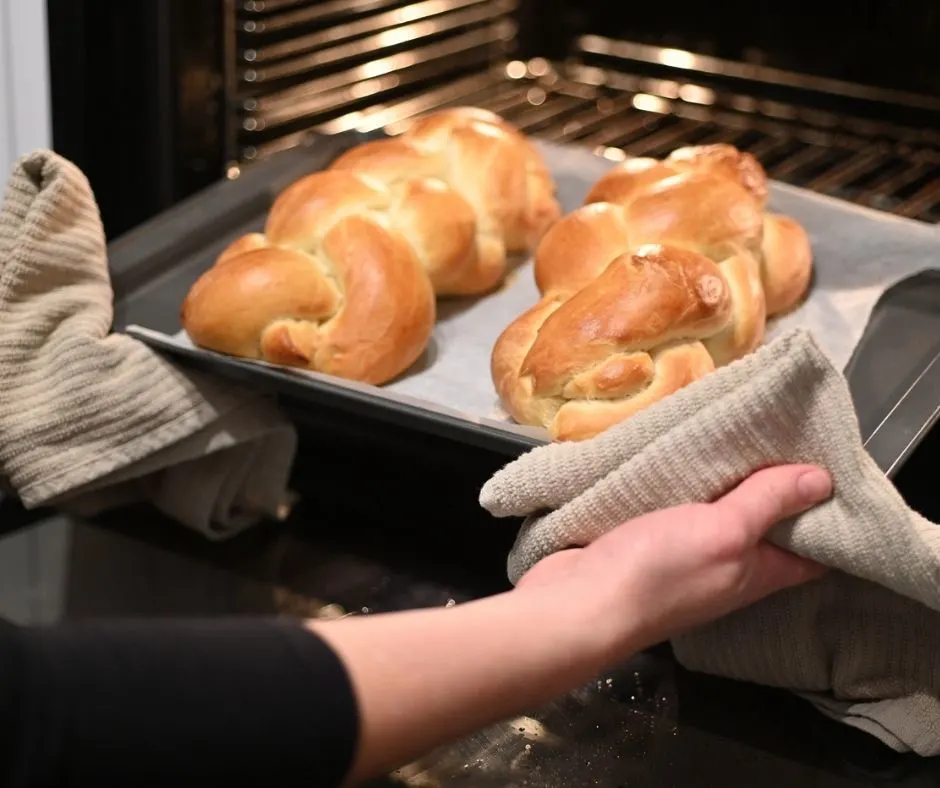 woman pulling out braided sausage bread from oven
