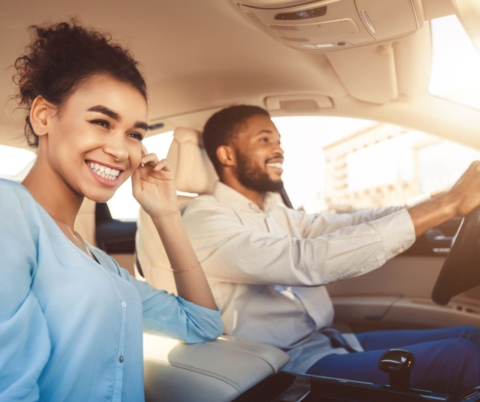 woman and man smiling, driving in car
