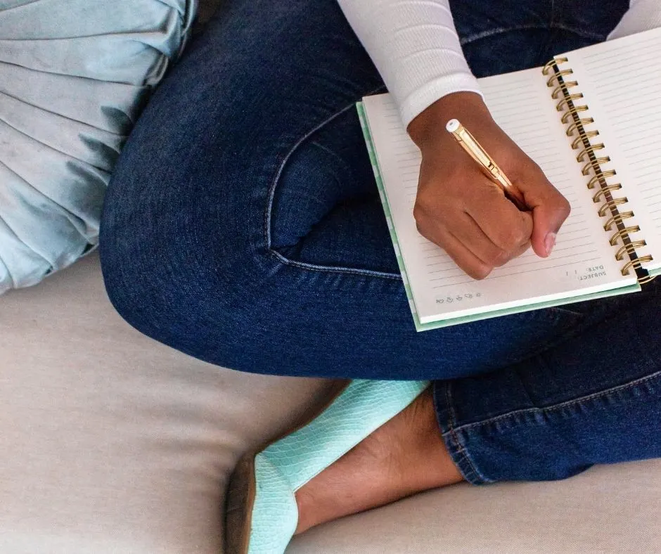 Woman in teal shoes on bed, looking ahead at personal calendar to budget annual expenses