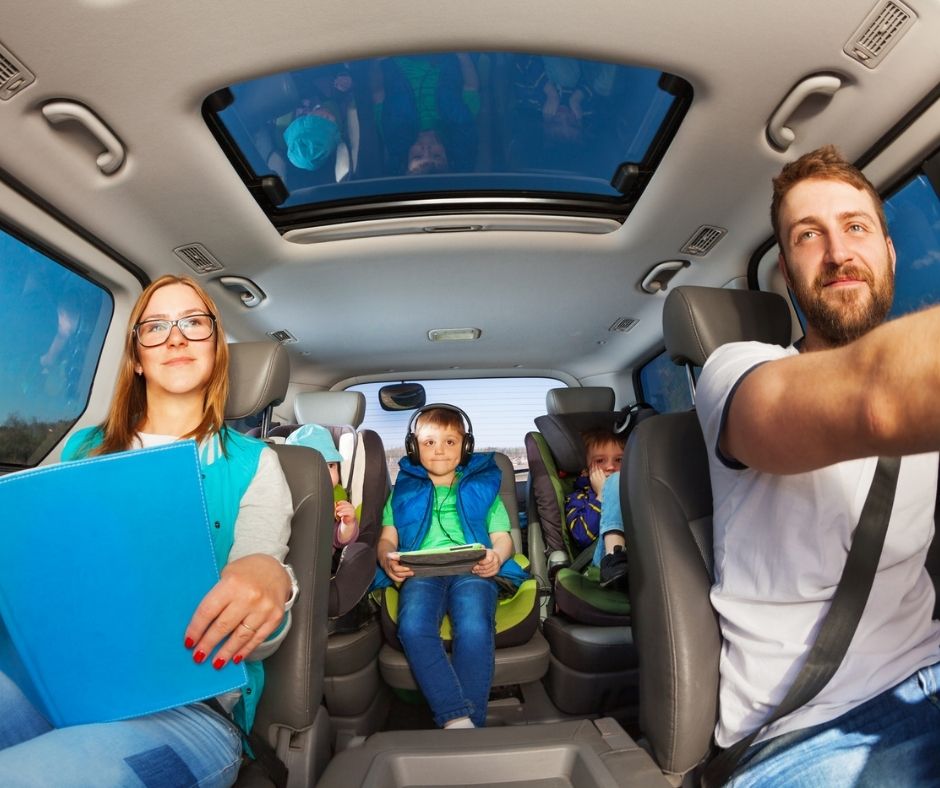 family in car after school, with kids listening to headphones