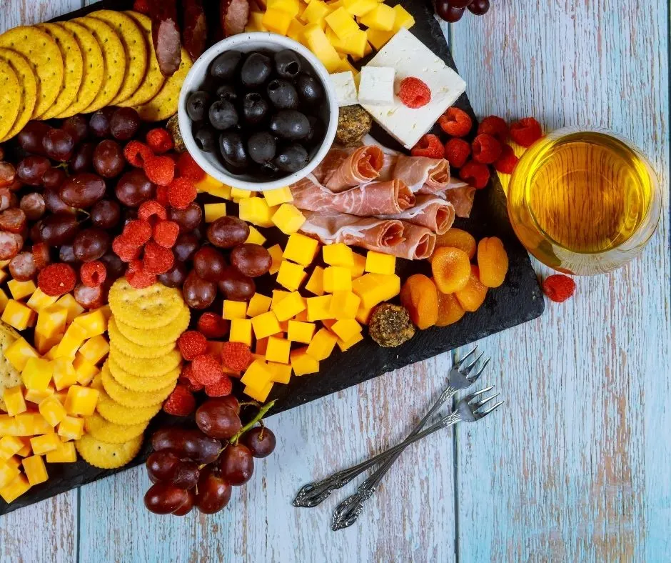 charcuterie board with fruits and cheeses on blue wooden table