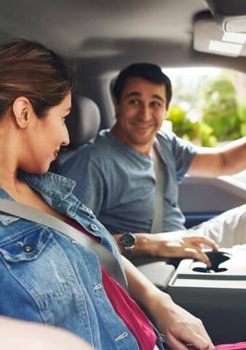 woman and man driving in car, smiling at each other