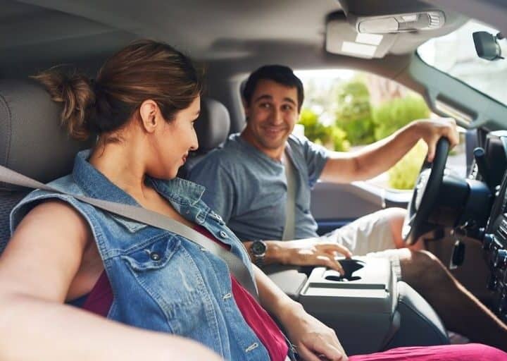 woman and man driving in car, smiling at each other