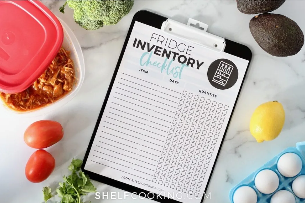 clipboard with fridge inventory checklist white printable and blue font on kitchen counter