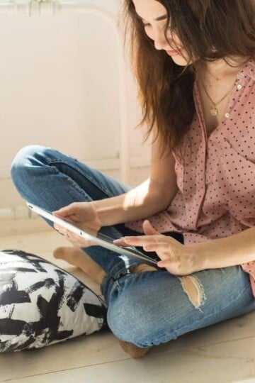 woman on floor with pillow and ipad, reading about starting a money savings challenge