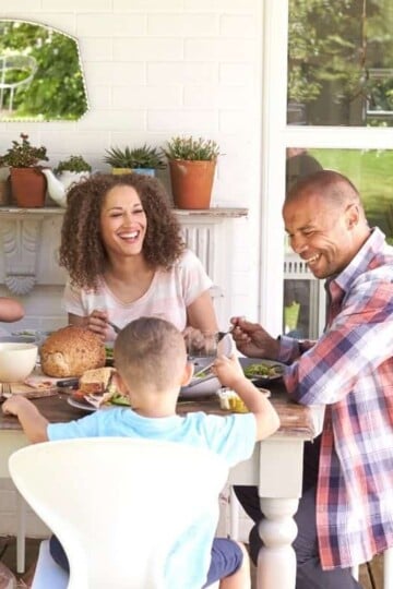 young family eating dinner at home on back patio