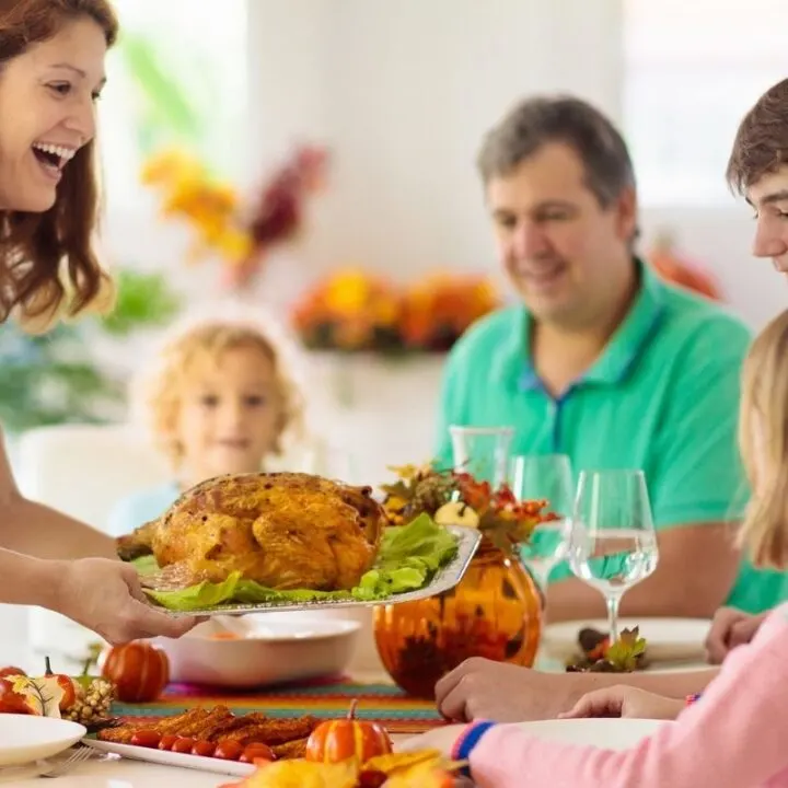 family of five with Mom holding turkey at table