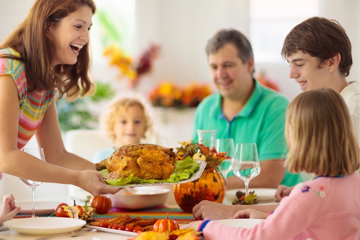 family of five with Mom holding turkey at table