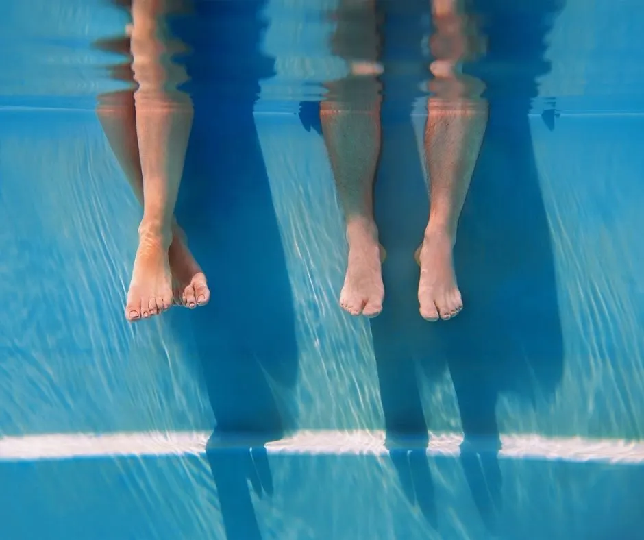 couple's legs dangled off the side of a pool