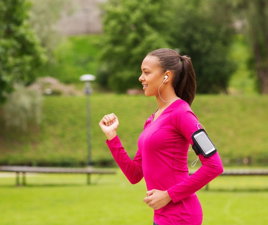 woman in pink run gear with phone on arm, speed-walking