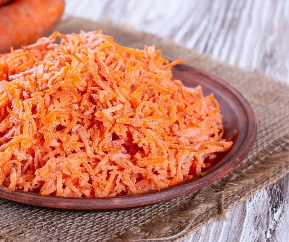 grated carrot salad on wooden plate on picnic table
