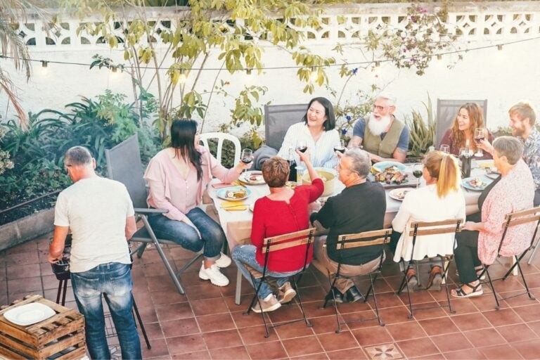 family reunion gathering at an outdoor picnic table, laughing and eating