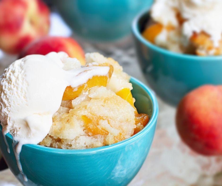peach cobbler in blue bowls on picnic table, with vanilla ice-cream