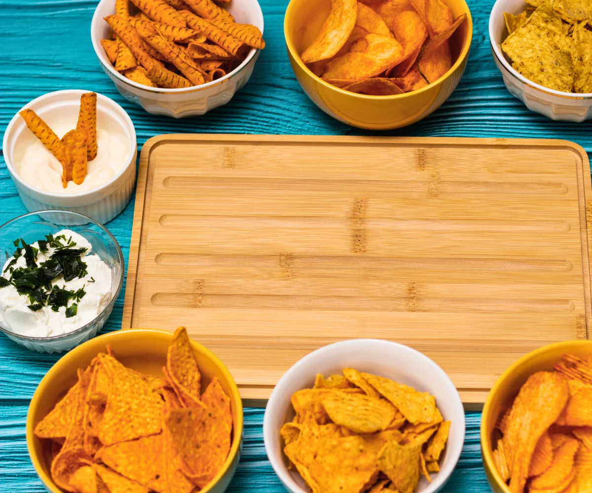 charcuterie board surrounded by dips and lots of different chips about to go on it