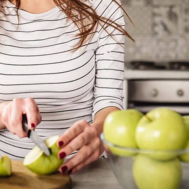 woman in black striped shirt chopping apples in kitchen for daniel fast menu plan