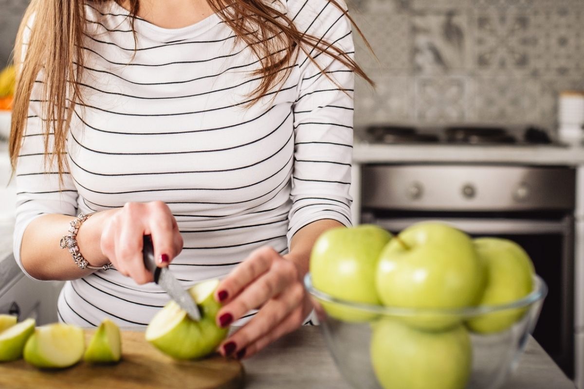 woman in black striped shirt chopping apples in kitchen for daniel fast menu plan