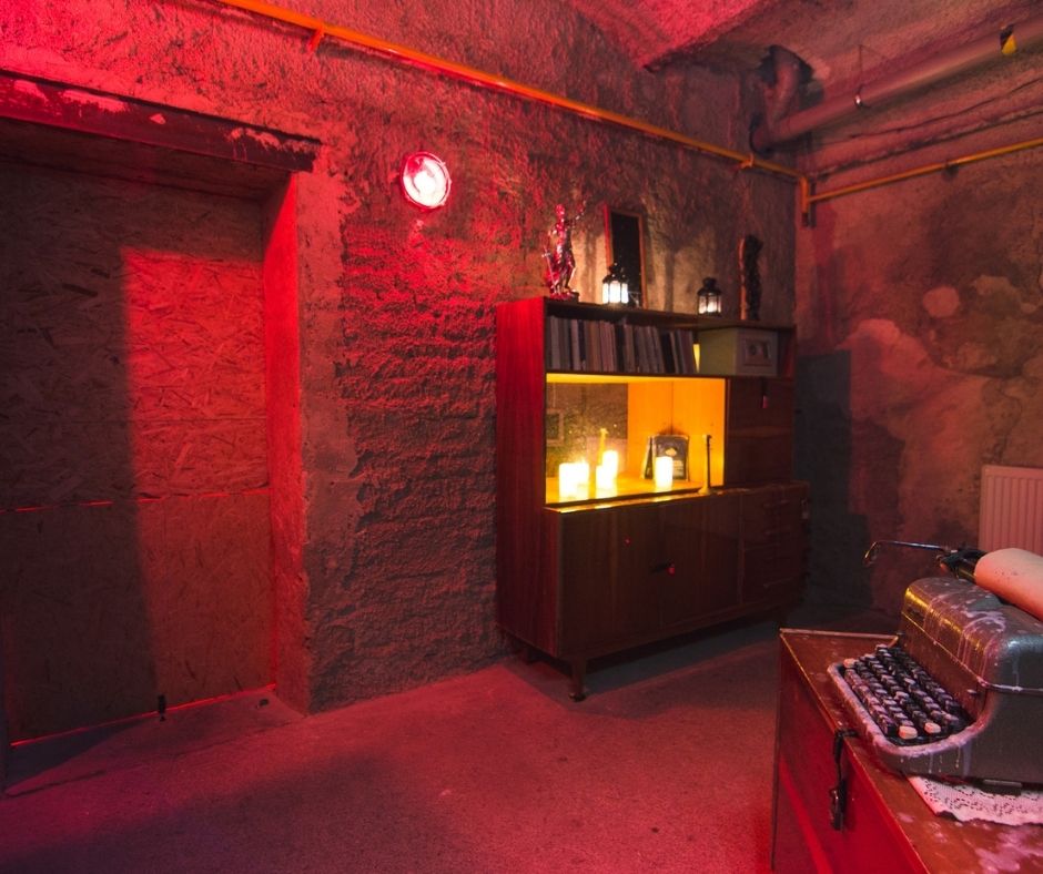 dark, red-lit escape room with a vintage typewriter and candles