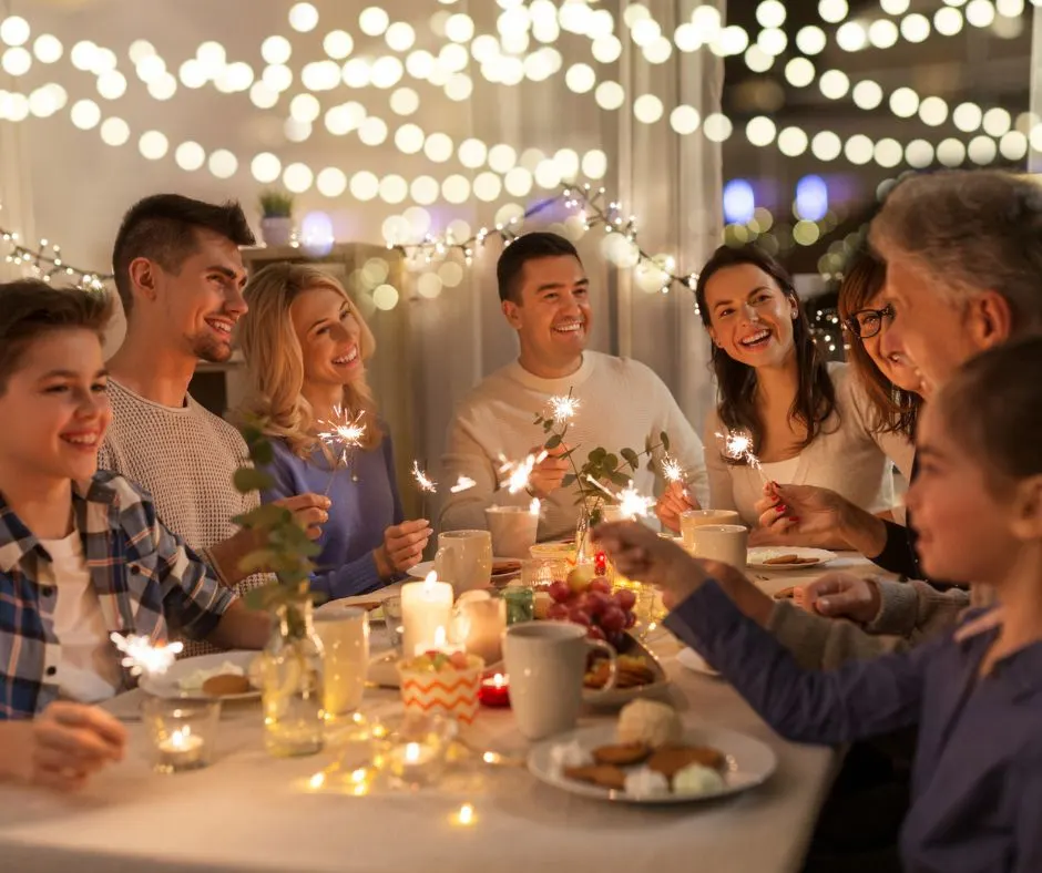 family all with sparklers, eating in back patio with Christmas lights above