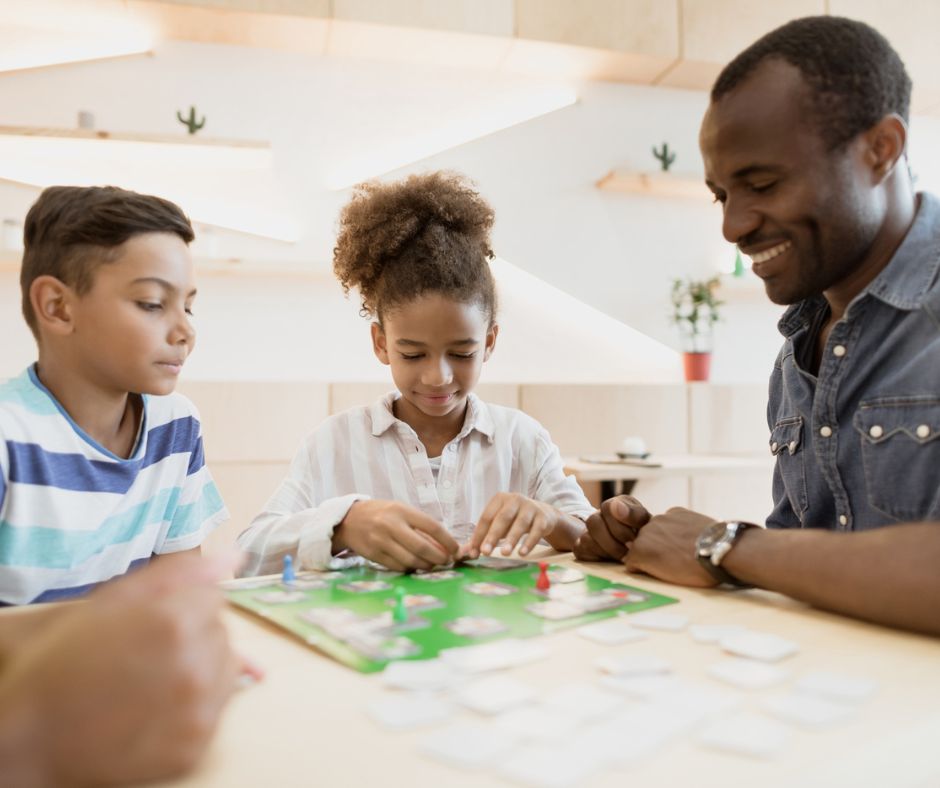 Dad and two kids playing board game together at table