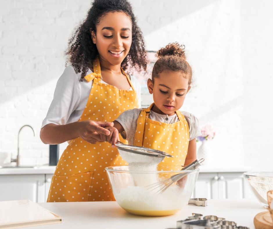 mother teacher daughter a recipe in white kitchen, wearing matching aprons