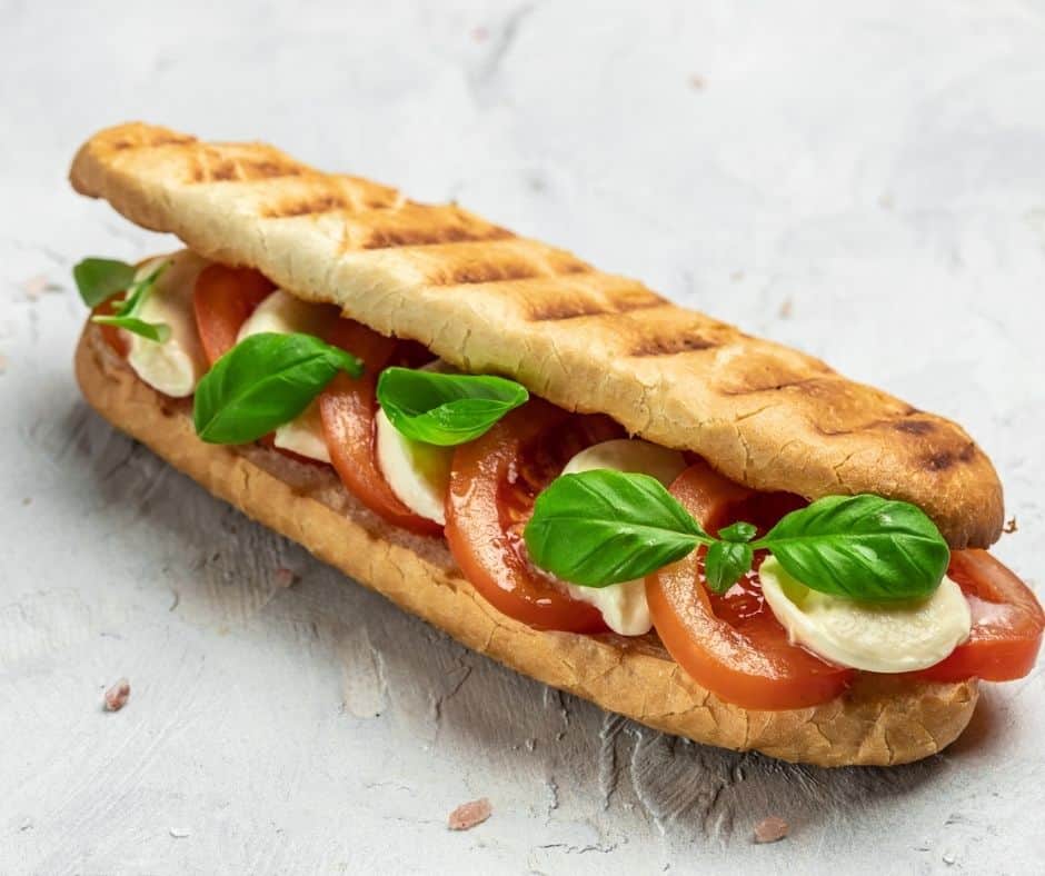 big caprese sandwich on white stone background