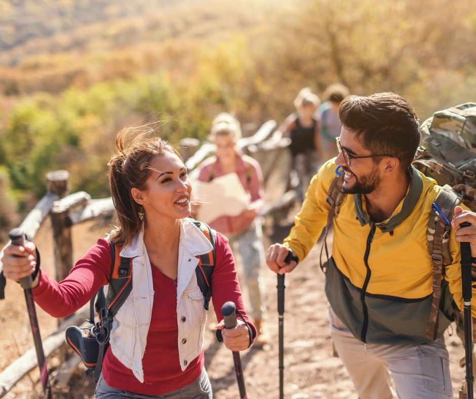 couple laughing while hiking to see peak foliage as a couple in the fall
