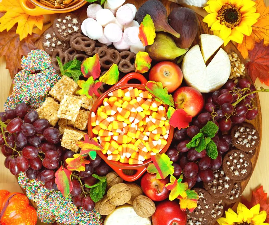 Thanksgiving themed charcuterie board on table, grapes, candy corn, cheese, etc.