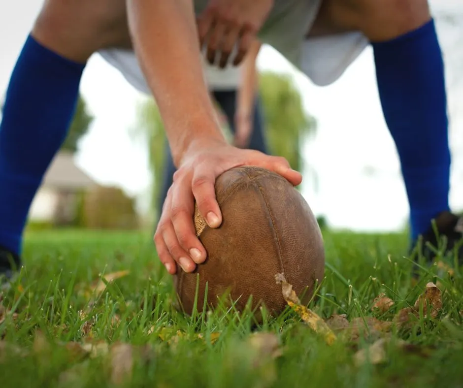 man kneeling with football, ready to play flag football with adult friends