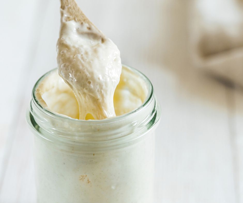 mason jar of sourdough starter with wooden spoon