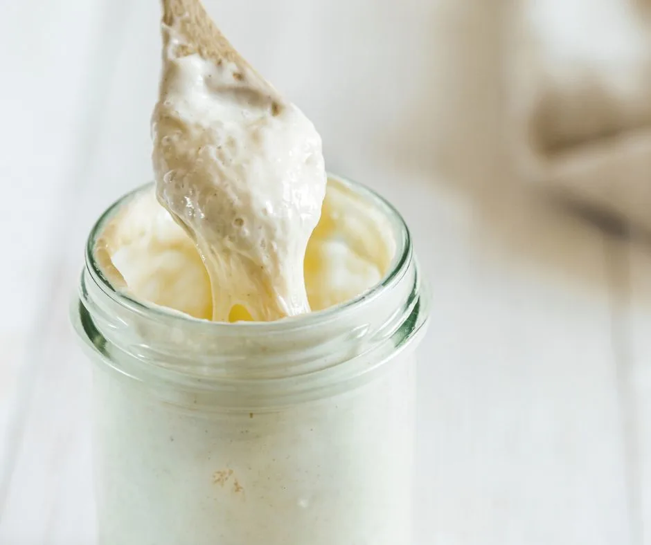 mason jar of sourdough starter with wooden spoon