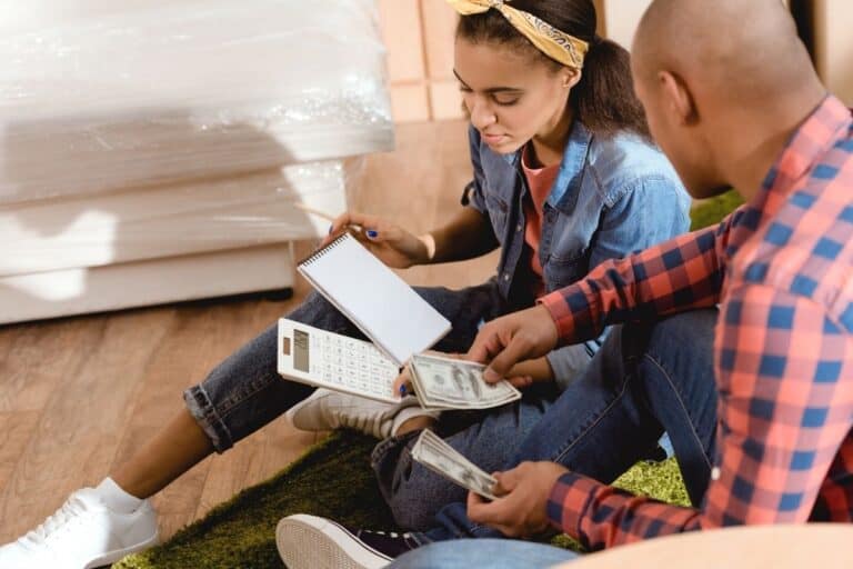 young married couple on ground talking about financial goals with calculator
