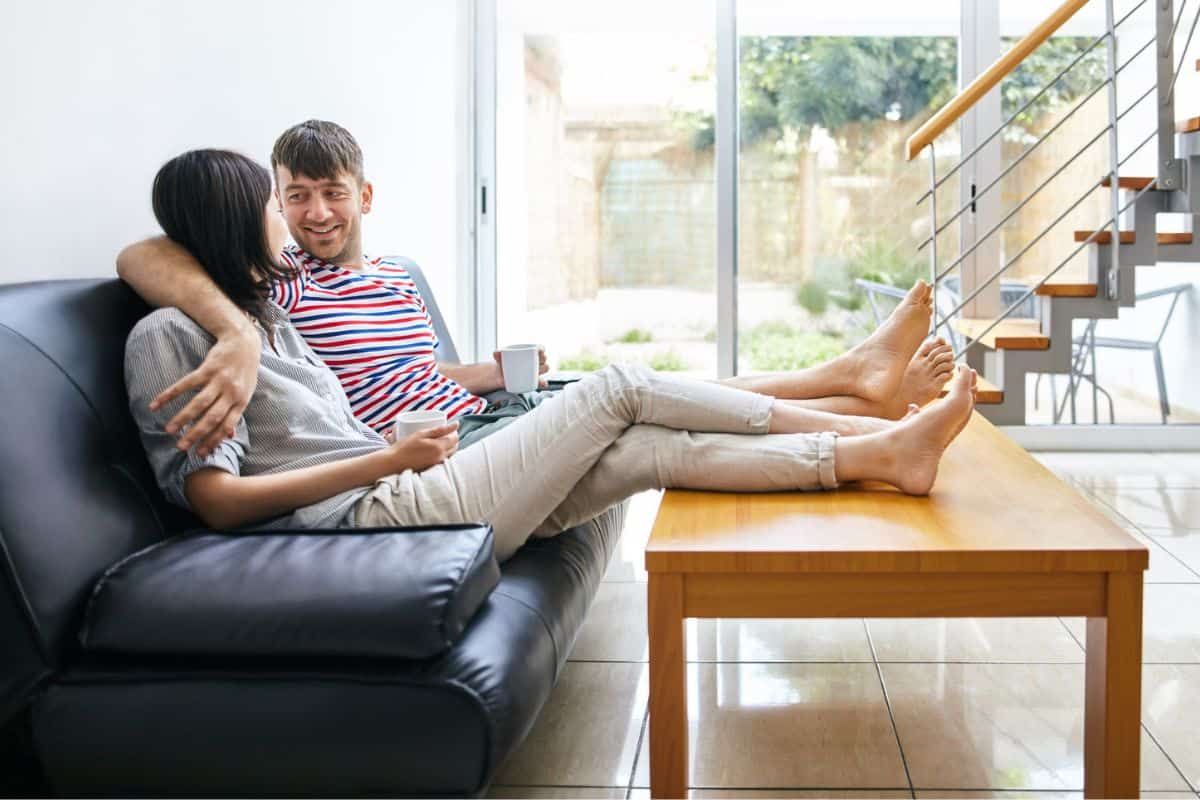 couple with arm around each other on couch, talking and facing each other