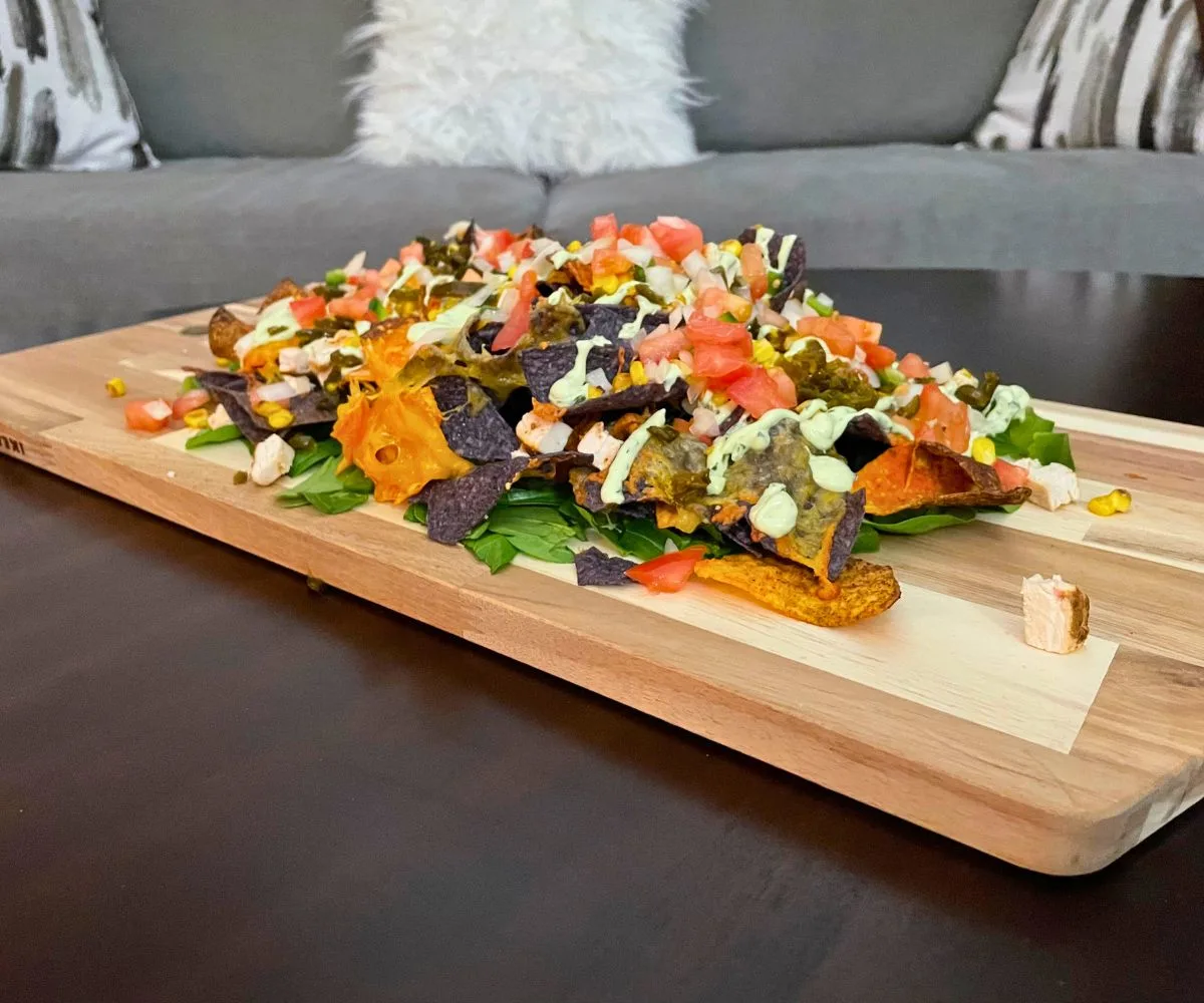 huge wooden board filled with yummy mountain of nachos with candied jalapenos, tomatoes, salsa, and so much more