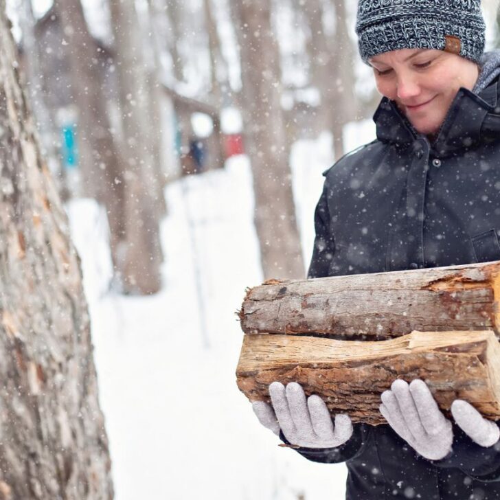 woman carrying wood in the snow, smiling