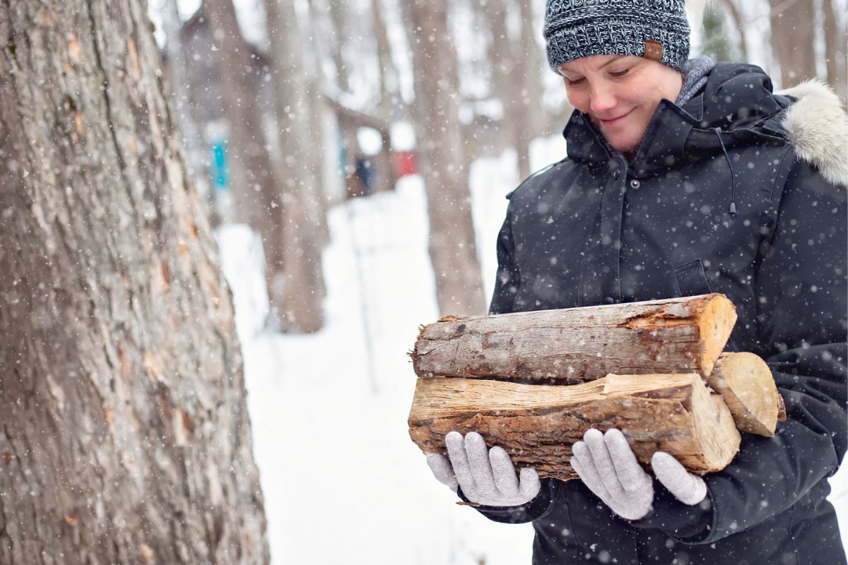 woman carrying wood in the snow, smiling