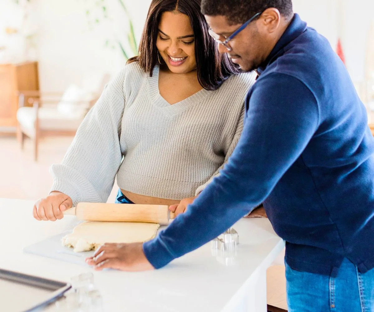 couple rolling out dough in the kitchen, having fun together