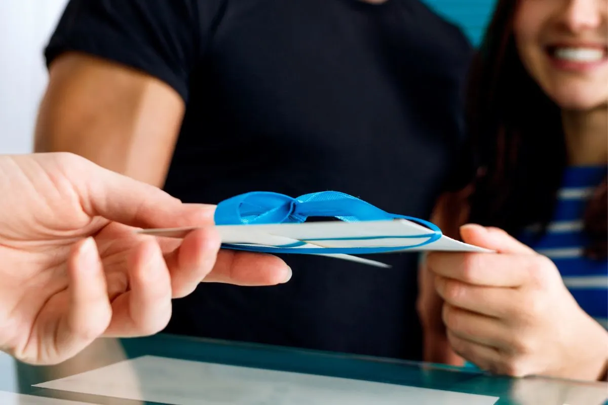 hands exchanging a money card with blue ribbon