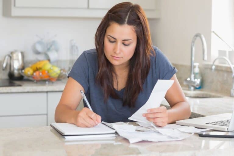 woman in blue shirt working at kitchen counter on family emergency binder